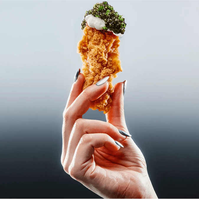 Hand holding a crispy chicken finger